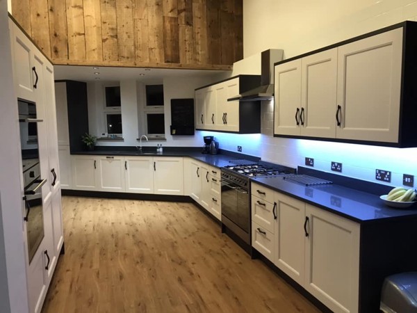 A kitchen fitted with under-cupboard lighting and wooden laminate flooring